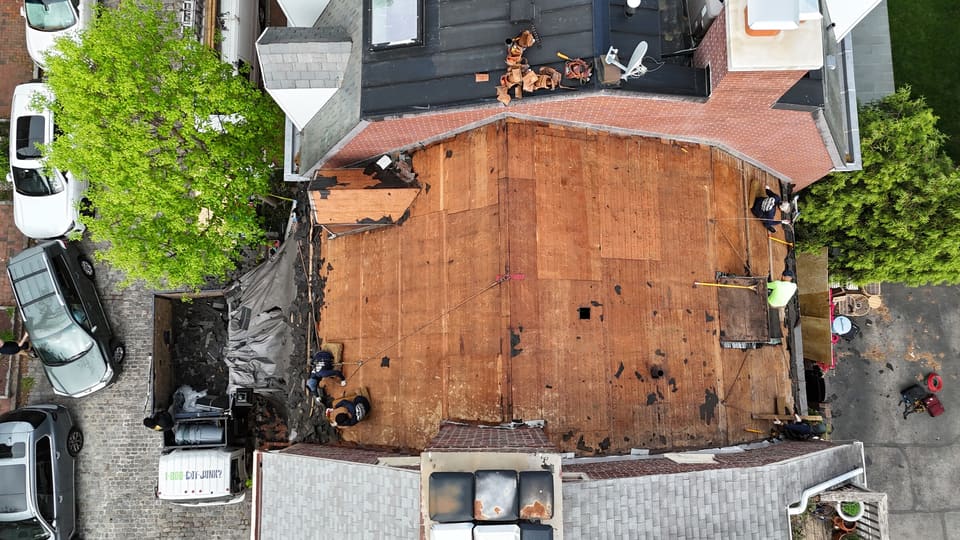 The same roof stripped to bare decking between the neighbors