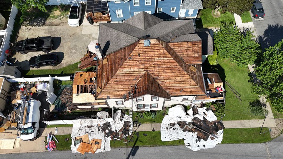 The same roof stripped back to the wood decking, crew on the slopes