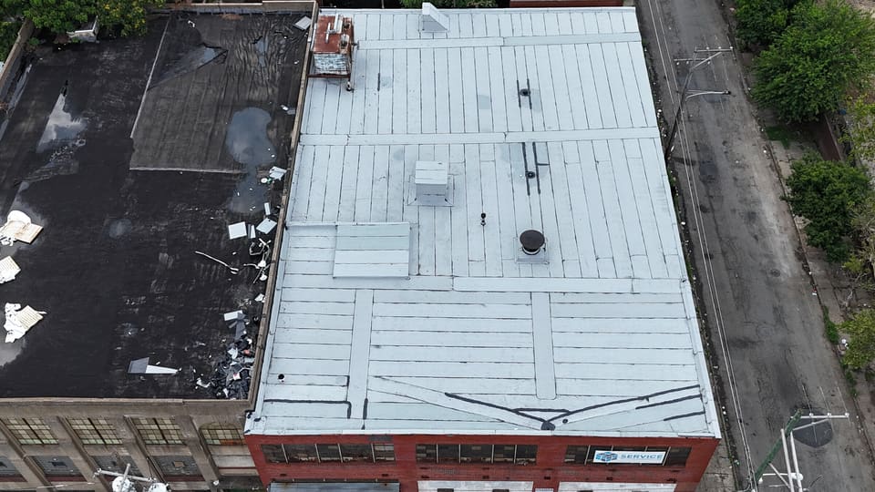 Drone view of a red brick commercial building with a silver coated flat roof