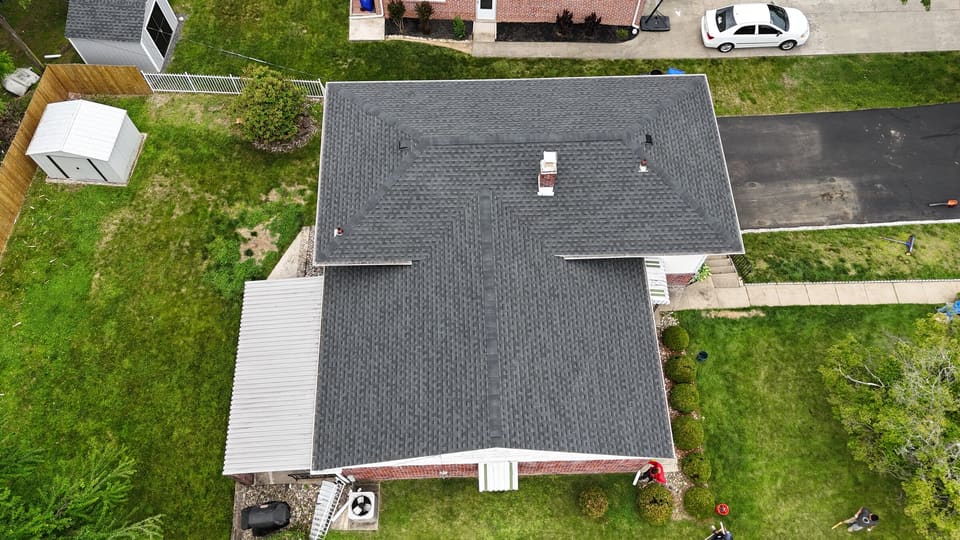 A finished dark grey shingle roof with a rear addition