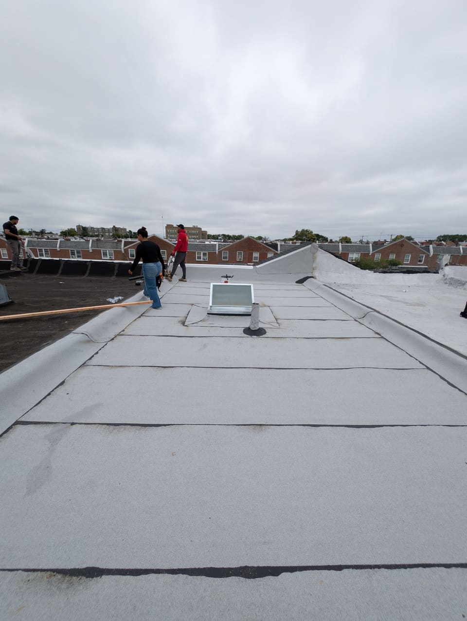 A finished grey flat roof with the crew in the distance