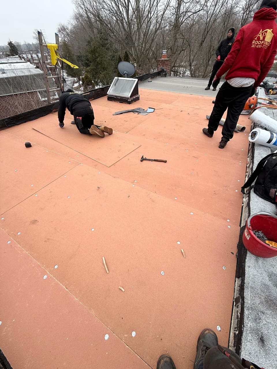 Crew laying new boards on a flat row home roof