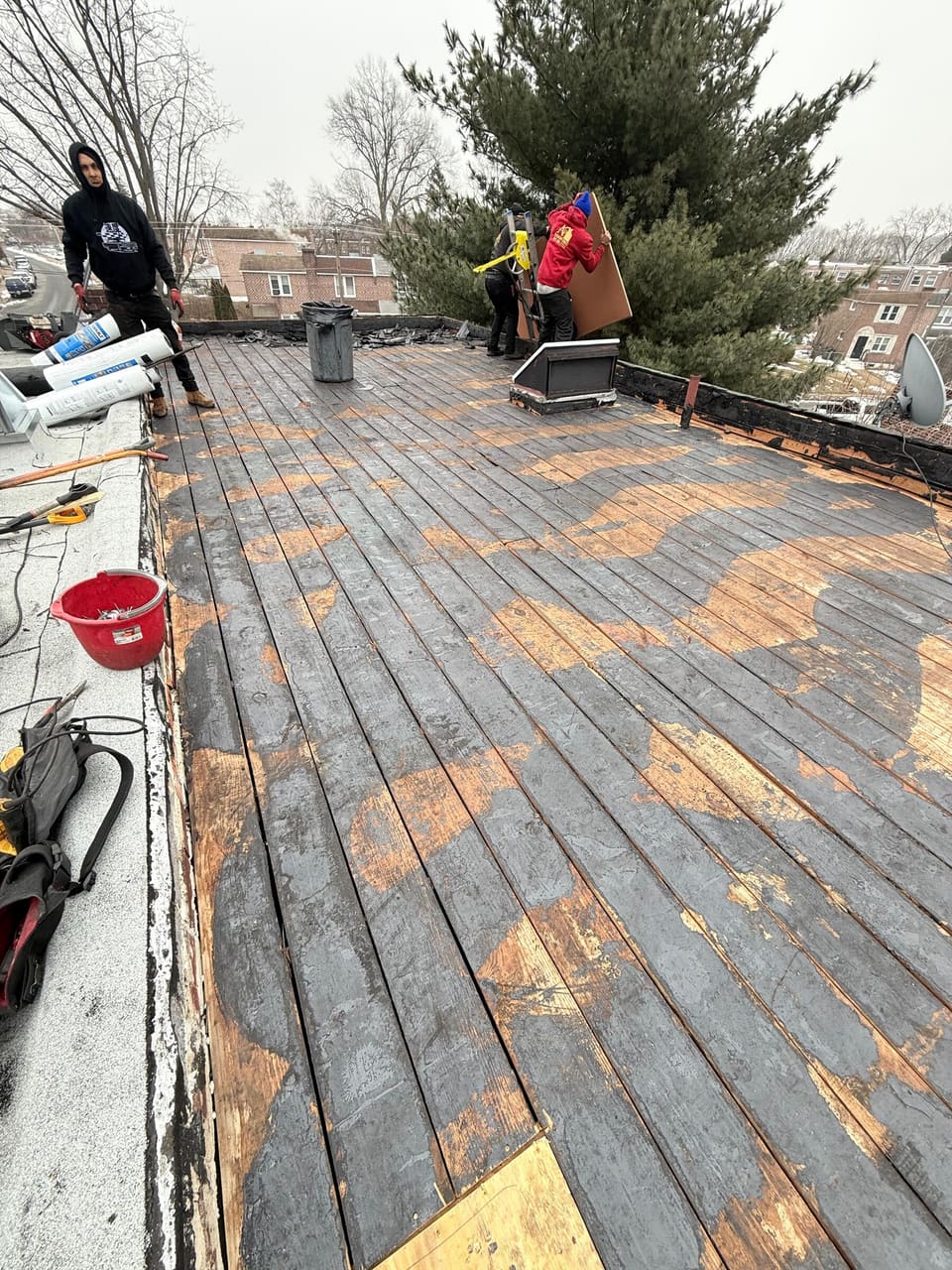A flat roof stripped back to the old boards, crew at work