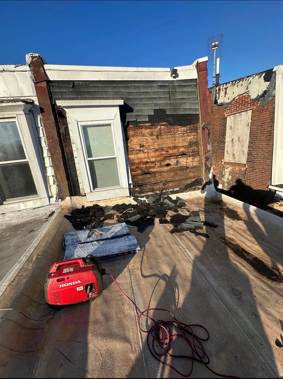 A row home rear roof torn off, generator and tools on the deck
