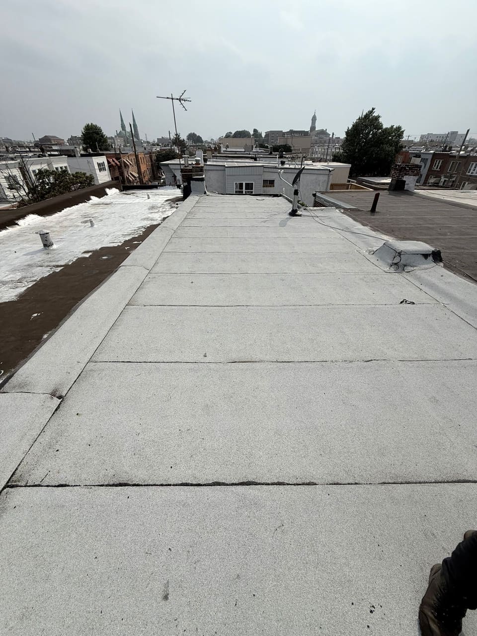 A coated flat roof on a winter day, snow on the roofs next door