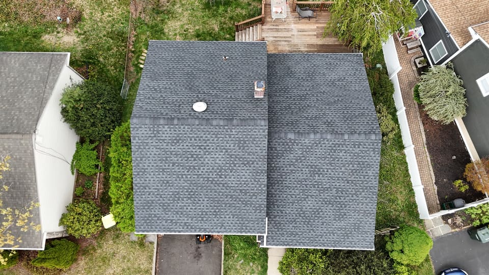 A finished grey shingle roof with a tidy yard below