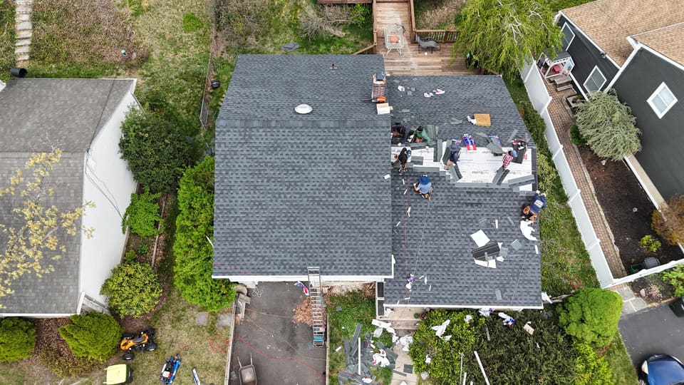 Grey shingles going on, with the old roofing piled in the yard