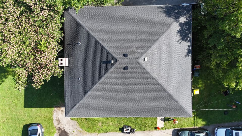 The finished hip roof with the yard and trees around it