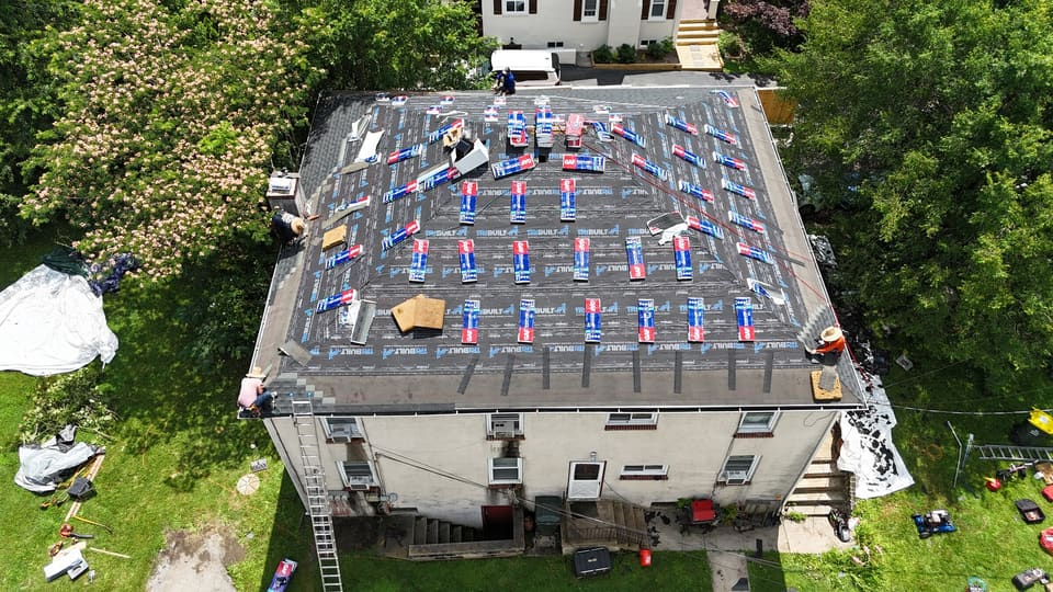 The same hip roof in underlayment with shingle bundles spread across it