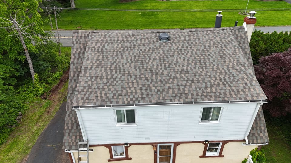 A finished roof from the drone, with a white gutter along the full eave and a downspout at the corner