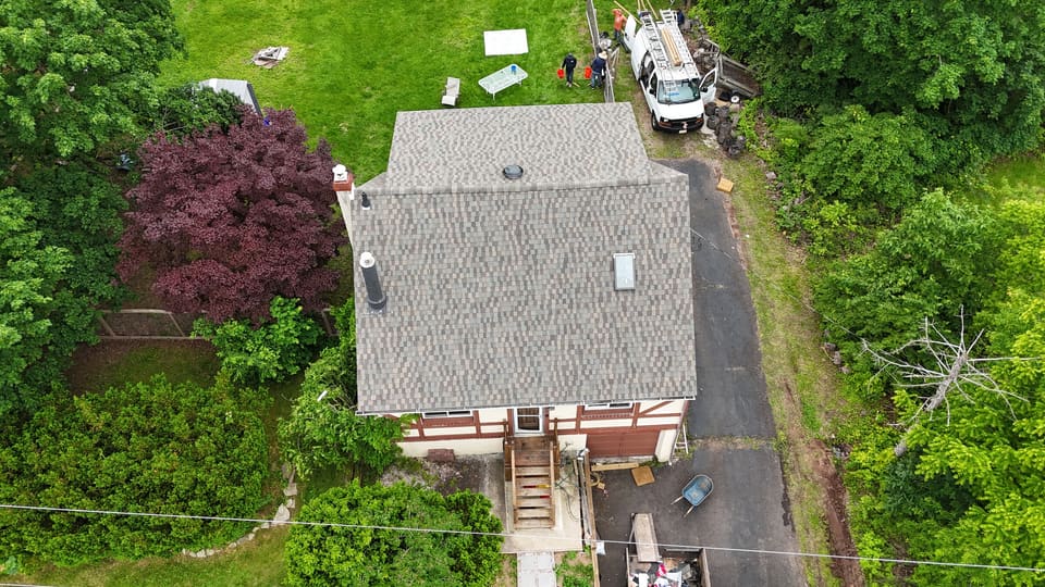 Drone view of the finished grey shingle roof next to the red maple