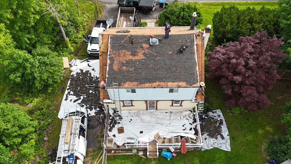 The old roof coming off, with a boom truck in the drive