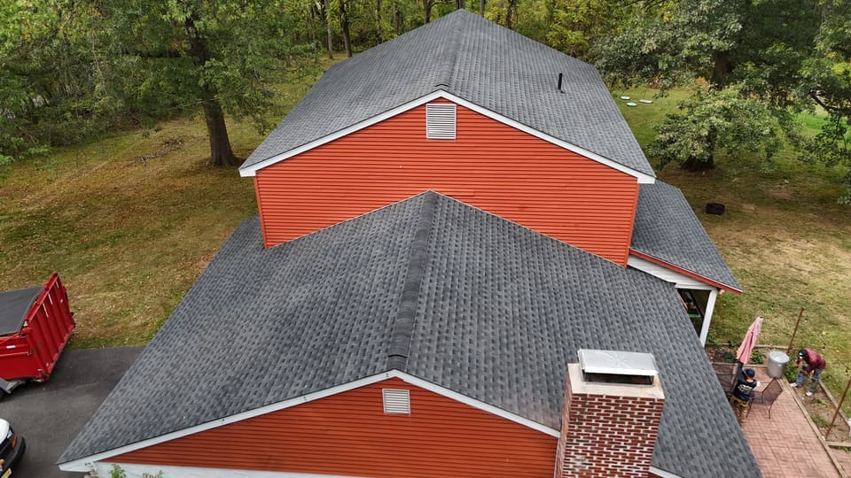 The finished grey shingle roof over orange siding