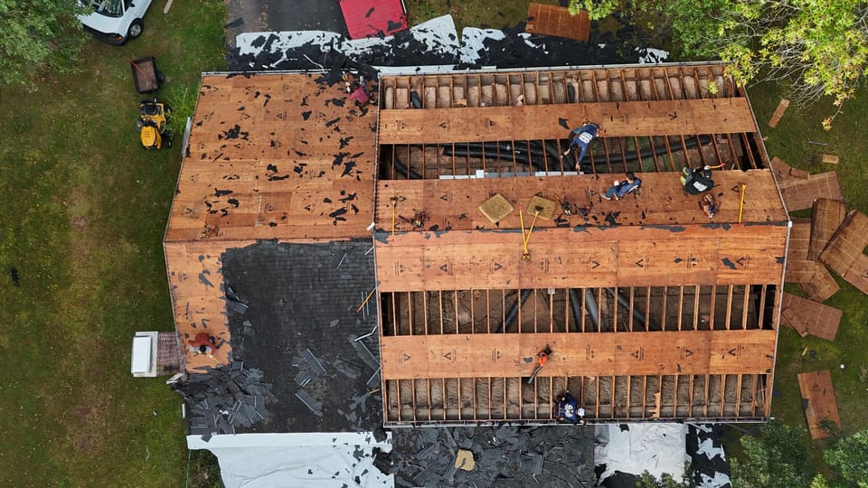 Drone view looking down the rafters of a roof opened up during a reroof