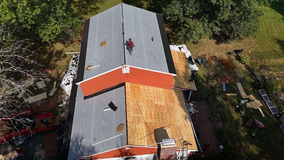 Underlayment going on over new decking above orange siding