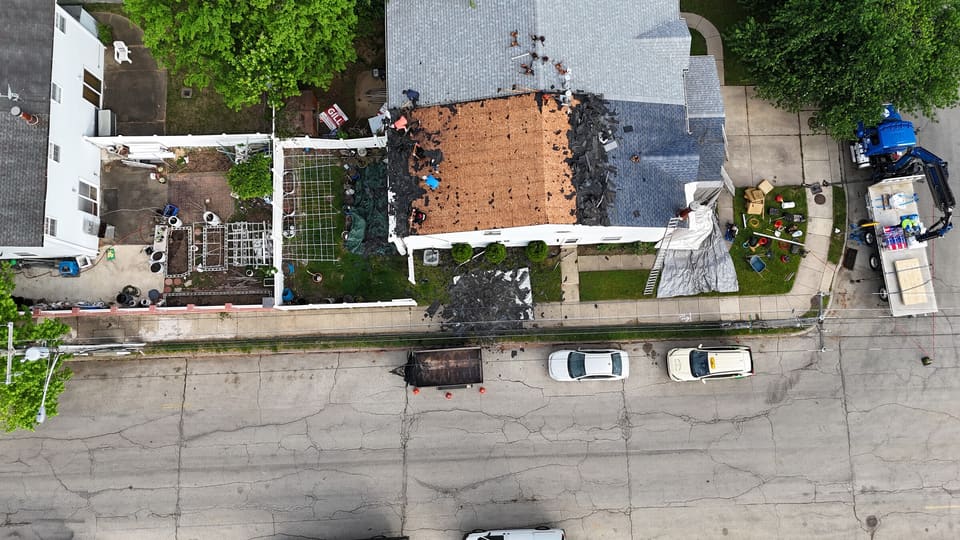 Drone view of a row of attached homes with one roof torn back