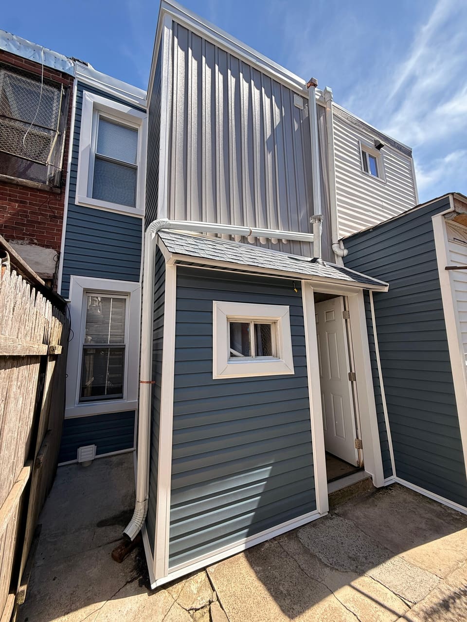The same row home rear in new blue siding with a white downspout