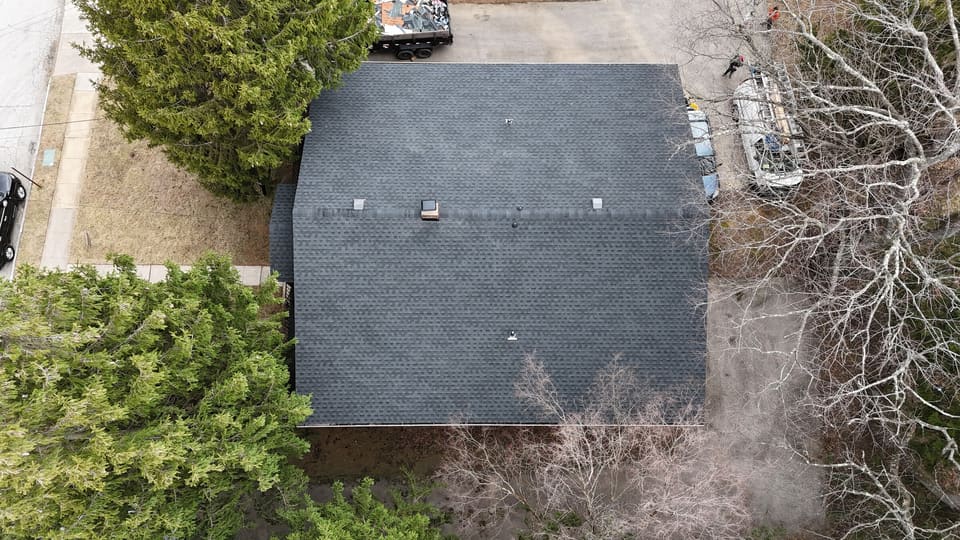 A finished dark grey shingle roof on a small house, from above