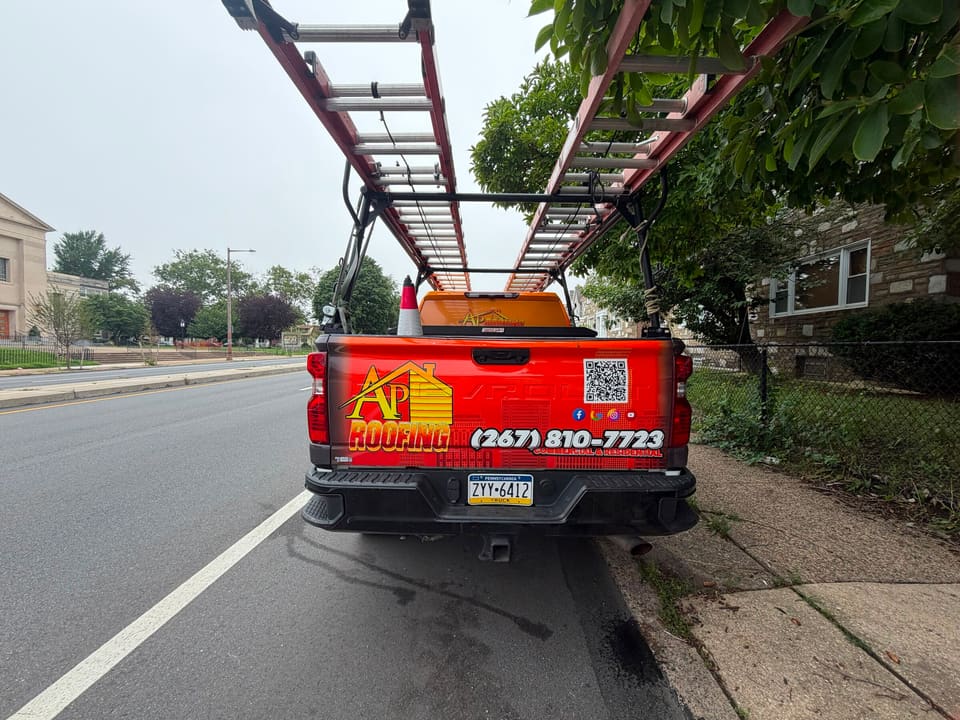 The back of an AP Roofing truck with the phone number and ladders
