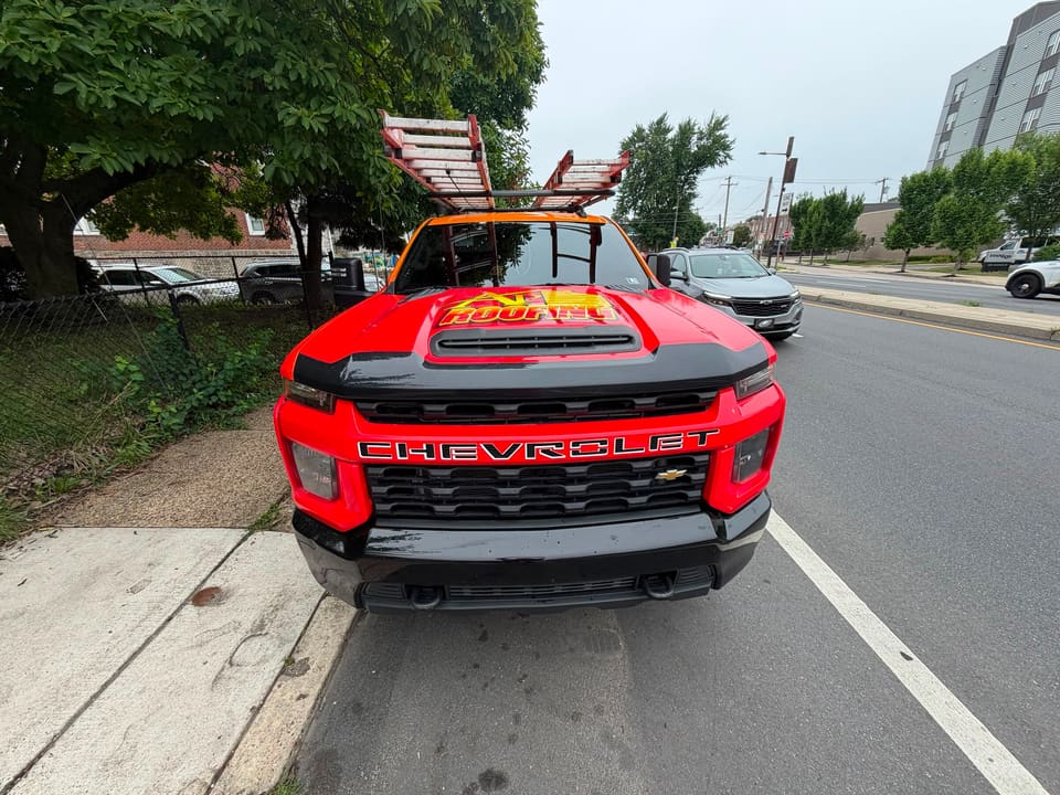 The red AP Roofing truck at a city curb